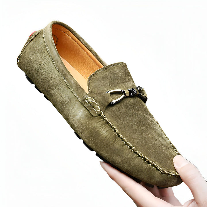 Mocassin en daim vert olive avec boucle métallique, tenu par une main. Chaussure homme élégante, confortable et décontractée. Idéal pour un look casual chic. Mode masculine, accessoires., 45286813466805,45286813499573,45286813532341,45286813565109,45286813597877,45286813630645,45286813663413,45286813696181,45286813728949,45286813761717,45286813794485,45286813827253,45286813860021,45286813892789,45286813925557,45286813958325,45286813991093,45286814023861,45286814056629,45286814089397,45286814122165,4
