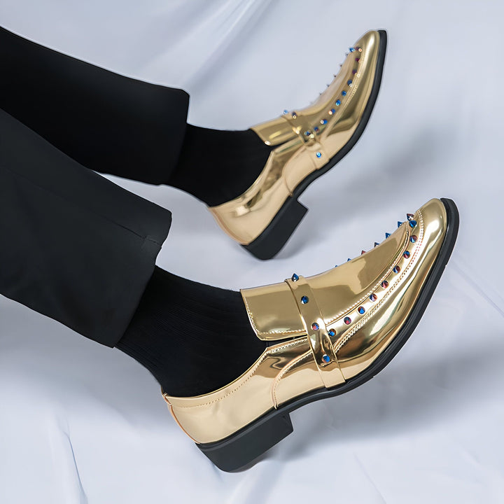 Gros plan de chaussures de ville dorées pour homme, avec détails cloutés bleus et rouges, portées avec un pantalon noir et des chaussettes noires. Style élégant et audacieux., 45286830309557,45286830342325,45286830375093,45286830407861,45286830440629,45286830473397,45286830506165,45286830538933