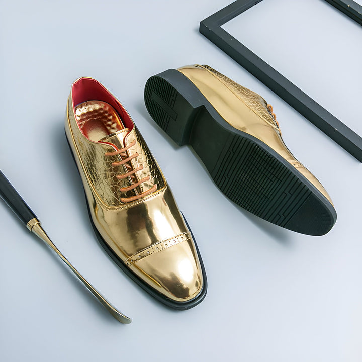 Chaussures richelieu dorées brillantes, avec lacets marron et motif texturé sur le dessus. Une paire est posée sur le côté, montrant la semelle noire. Un chausse-pied et un cadre noir complètent la composition., 45286821167285,45286821200053,45286821232821,45286821265589,45286821298357,45286821331125,45286821363893