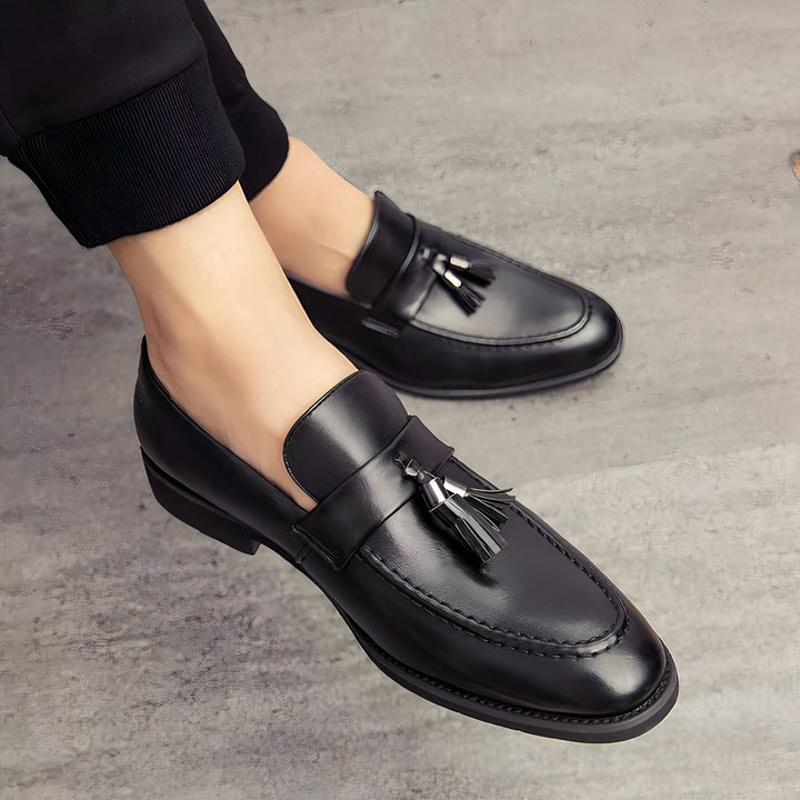 Gros plan sur des mocassins noirs en cuir à glands pour homme, portés avec un pantalon noir. Chaussures élégantes, mode masculine, style classique., 45286937690293,45286937723061,45286937755829,45286937788597,45286937821365,45286937854133,45286937886901,45286937919669,45286937952437,45286937985205,45286938017973,45286938050741,45286938083509,45286938116277,45286938149045,45286938181813,45286938214581,45286938247349