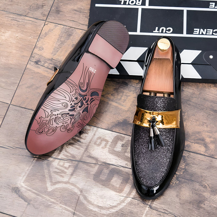 Gros plan sur une paire de mocassins vernis noirs élégants, avec une boucle dorée et des glands décoratifs. On aperçoit la semelle ornée de motifs et une claquette de cinéma en arrière-plan., 45287088226485,45287088259253,45287088292021,45287088324789,45287088357557,45287088390325,45287088423093,45287088455861,45287088488629,45287088521397