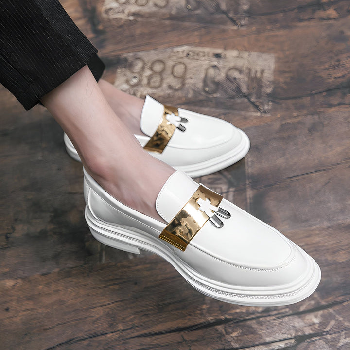 Gros plan sur une paire de mocassins blancs vernis avec une bride dorée, portés par une personne en pantalon noir à rayures. Les chaussures sont posées sur un fond en bois texturé avec des inscriptions. Idéal pour la mode masculine et le style élégant., 45286847807669,45286847840437,45286847873205,45286847905973,45286847938741,45286847971509,45286848004277