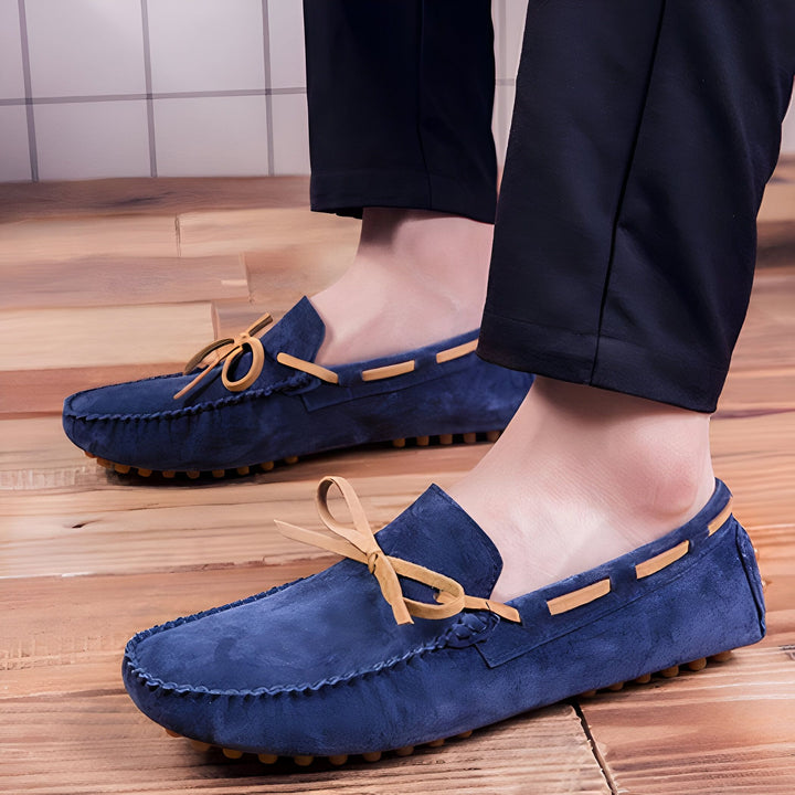 Gros plan de mocassins bleus pour hommes en daim avec lacets en cuir clair, portés avec un pantalon noir sur un plancher en bois. Chaussures confortables et élégantes., 45287109853365,45287110082741,45287110115509,45287110148277,45287110181045,45287110213813,45287110246581