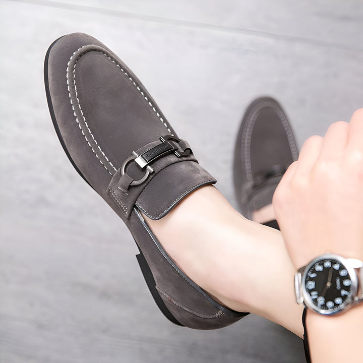 Mocassins gris en daim pour homme avec boucle métalique et surpiqûres blanches, portés avec une montre bracelet élégante. Chaussures de ville décontractées et confortables, parfaites pour un look raffiné., 45286814286005,45286814318773,45286814351541,45286814384309,45286814417077,45286814449845,45286814482613,45286814515381,45286814548149,45286814580917,45286814613685,45286814646453,45286814679221,45286814711989,45286814744757,45286814777525,45286814810293,45286814843061,45286814875829,45286814908