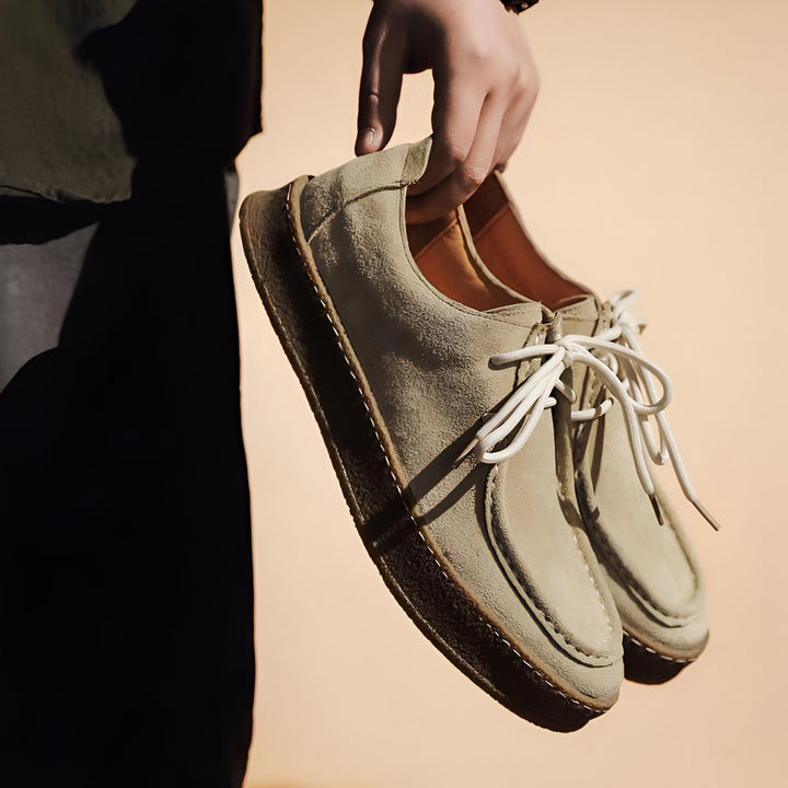 Gros plan d'une personne tenant une paire de chaussures décontractées en daim beige avec des lacets blancs. La semelle est épaisse et foncée. Style élégant et confortable., 45286978191541,45286978224309,45286978257077,45286978289845,45286978322613,45286978355381,45286978388149,45286978420917,45286978453685,45286978486453,45286978519221,45286978551989,45286978584757,45286978617525,45286978650293,45286978683061,45286978715829,45286978748597,45286978781365,45286978814133,45286978846901