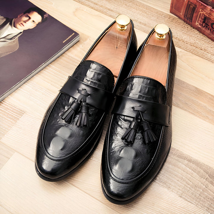 Gros plan sur une paire de mocassins noirs à pampilles en cuir texturé, présentés avec des embauchoirs. Un magazine et un livre sont visibles en arrière-plan sur un plancher en bois., 45286935756981,45286935789749,45286935822517,45286935855285,45286935888053,45286935920821,45286935953589,45286935986357,45286936019125,45286936051893,45286936084661,45286936117429,45286936150197,45286936182965,45286936215733,45286936248501,45286936281269,45286936314037,45286936346805,45286936379573