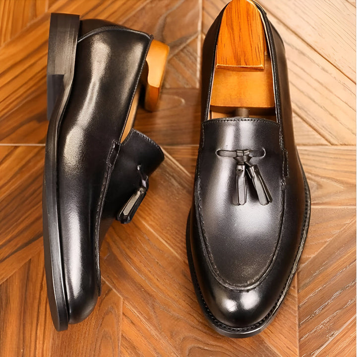 Image de deux mocassins en cuir noir élégants, avec des glands décoratifs et des embauchoirs en bois. Les chaussures sont placées sur un parquet en bois, créant une ambiance luxueuse et soignée. Idéal pour la mode masculine et le style classique., 45286723518645,45286723551413,45286723584181,45286723616949,45286723649717,45286723682485,45286723715253,45286723748021,45286723780789,45286723813557,45286723846325,45286723879093,45286723911861,45286723944629