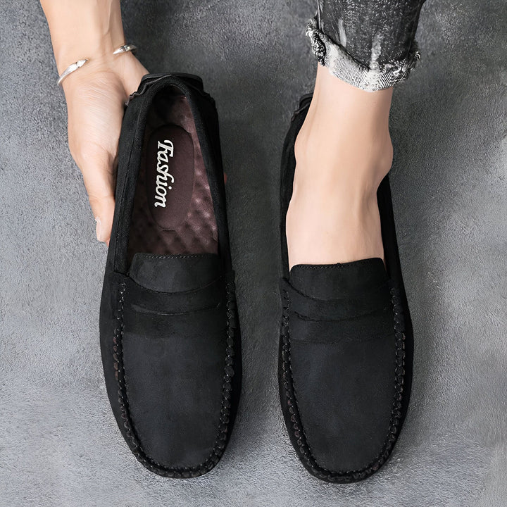 Vue du dessus de mocassins noirs en daim pour hommes, portés sur un pied et tenus à la main. Chaussures confortables et élégantes, parfaites pour un look décontracté et sophistiqué., 45287111229621,45287111262389,45287111295157,45287111327925,45287111360693,45287111393461,45287111426229