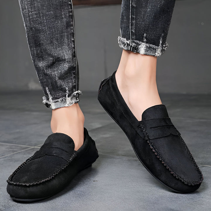 Gros plan sur des mocassins noirs en daim portés avec un jean délavé. Chaussures décontractées pour homme, style mode urbaine. Mocassins élégants et confortables., 45287111229621,45287111262389,45287111295157,45287111327925,45287111360693,45287111393461,45287111426229