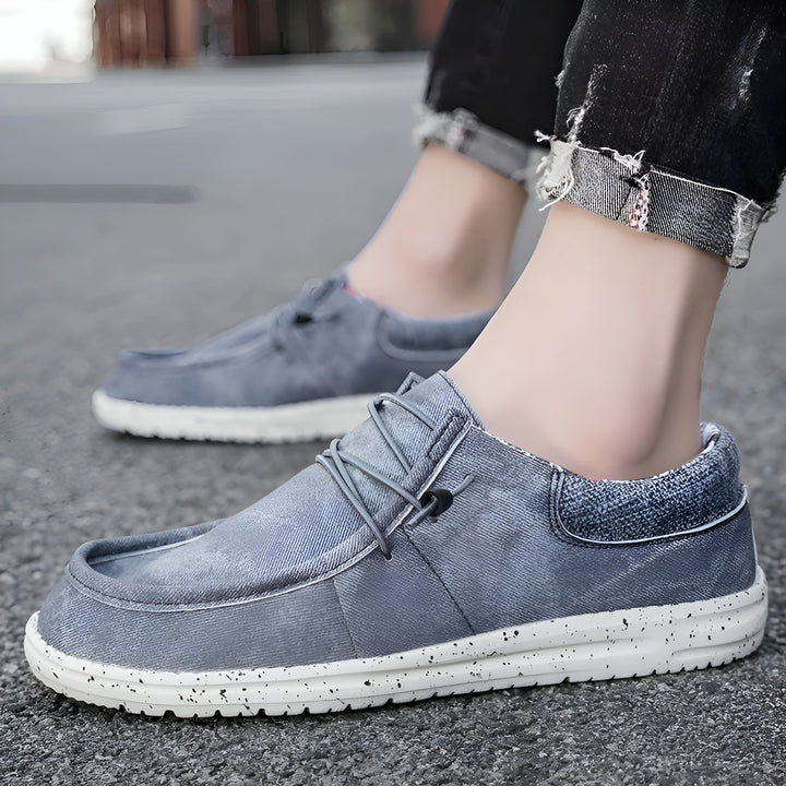 Gros plan sur une paire de chaussures décontractées en denim bleu avec des lacets gris et des semelles blanches mouchetées portées par une personne en jean noir., 45286671614133,45286671646901,45286671679669,45286671712437,45286671745205,45286671777973,45286671810741,45286671843509,45286671876277,45286671909045,45286671941813,45286671974581,45286672007349,45286672040117,45286672072885,45286672105653,45286672138421,45286672171189,45286672203957,45286672236725,45286672269493,45286672302261,4528667233502