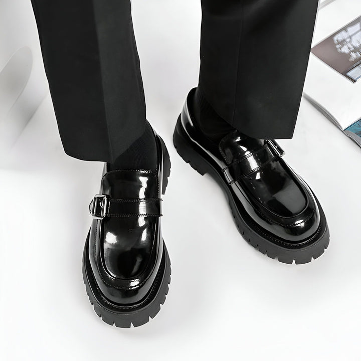 Gros plan sur une personne portant des mocassins noirs vernis à boucle, associées à un pantalon noir, sur fond blanc. Mise en valeur du style et de l'élégance des chaussures., 45286900138165,45286900170933,45286900203701,45286900236469,45286900269237,45286900302005,45286900334773