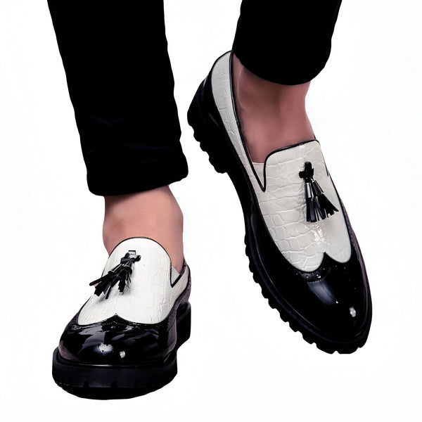 Homme portant des mocassins bicolores noir et blanc avec glands, pantalon noir. Chaussures élégantes en cuir verni et imitation croco, style original et tendance. Mode masculine., 45287061323957,45287061356725,45287061389493,45287061422261,45287061455029,45287061487797,45287061520565,45287061553333,45287061586101