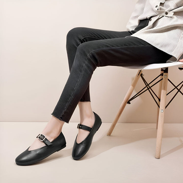 Image d'une femme assise sur une chaise portant des chaussures plates noires à boucle et un jean noir. Style décontracté et élégant. Chaussures confortables., 45286701596853,45286701629621,45286701662389,45286701695157,45286701727925,45286701760693,45286701793461,45286701826229,45286701858997