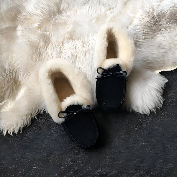Vue rapprochée de chaussons noirs en suède doublés de fausse fourrure blanche, avec des nœuds décoratifs, posés sur une peau de mouton blanche moelleuse et un fond noir texturé. Confort et style pour l'intérieur., 45286951452853,45286951485621,45286951518389,45286951551157,45286951583925,45286951616693,45286951649461,45286951682229,45286951714997,45286951747765,45286951780533,45286951813301,45286951846069,45286951878837,45286951911605,45286951944373,45286951977141,45286952009909,45286952042677,452