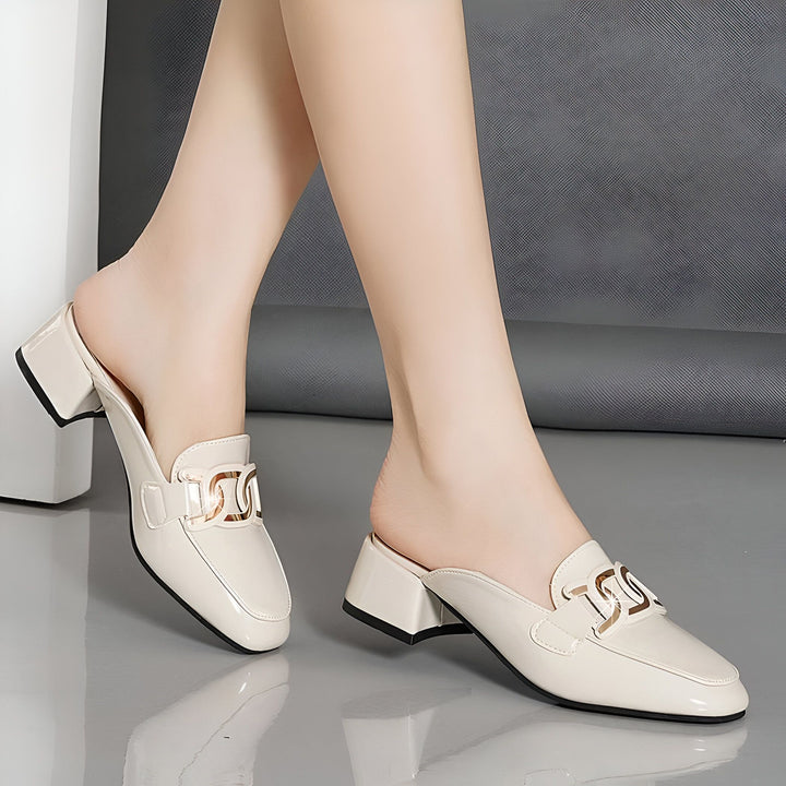 Gros plan sur des mules vernies couleur crème, avec un talon carré noir et une boucle dorée. Chaussures élégantes et confortables pour femme., 45286907936949,45286907969717,45286908002485,45286908035253,45286908068021,45286908100789,45286908133557,45286908166325,45286908199093,45286908231861,45286908264629,45286908297397