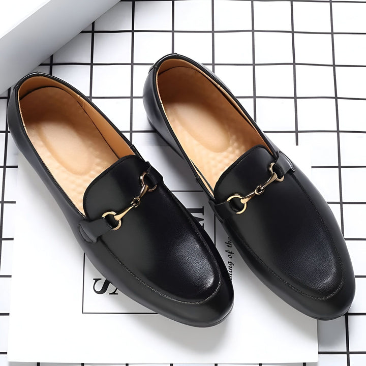 Photo de deux mocassins noirs en cuir avec une boucle dorée, posés sur un fond à carreaux blancs et noirs. Chaussures élégantes et classiques pour homme., 45286696747189,45286696779957,45286696812725,45286696845493,45286696878261,45286696911029