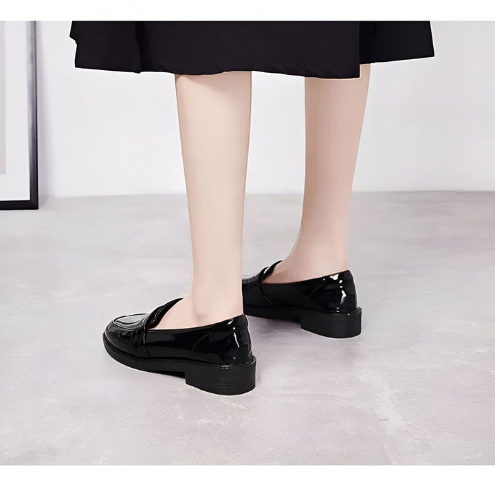 Gros plan sur une femme portant des mocassins noirs vernis et une jupe noire, montrant le style élégant et les chaussures tendance., 45286725910709,45286725943477,45286725976245,45286726009013,45286726041781,45286726074549,45286726107317