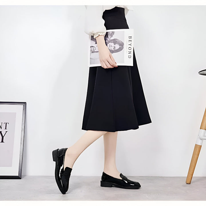 Image d'une femme portant une jupe noire et des mocassins noirs vernis. Elle tient un magazine intitulé "Beyond"., 45286725910709,45286725943477,45286725976245,45286726009013,45286726041781,45286726074549,45286726107317