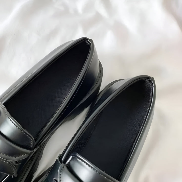 Gros plan sur une paire de mocassins noirs vernis sur un fond blanc. Chaussures élégantes pour femme, style preppy ou uniforme. Mode automne-hiver., 45286720700597,45286720733365,45286720766133,45286720798901,45286720831669,45286720864437,45286720897205,45286720929973,45286720962741