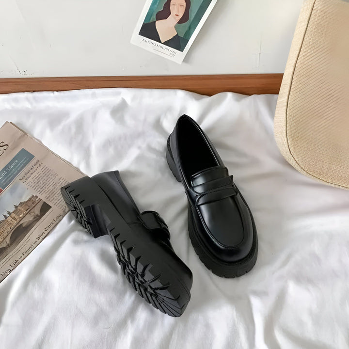 Paire de mocassins noirs à semelle épaisse sur un drap blanc, avec un journal, un sac et une carte postale en arrière-plan. Chaussures à la mode, style preppy, confort et design., 45286720700597,45286720733365,45286720766133,45286720798901,45286720831669,45286720864437,45286720897205,45286720929973,45286720962741