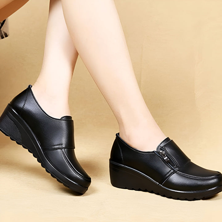 Gros plan sur des pieds chaussés d'escarpins compensés noirs en cuir. Élégance et confort au quotidien., 45286892667061,45286892699829,45286892732597,45286892765365,45286892798133,45286892830901,45286892863669