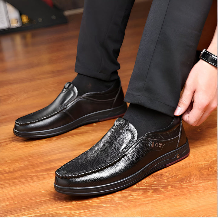 Homme portant des mocassins noirs en cuir avec un pantalon noir et des chaussettes noires, assis sur un parquet en bois. Gros plan sur les chaussures élégantes., 45286938411189,45286938443957,45286938476725,45286938509493,45286938542261,45286938575029,45286938607797,45286938640565,45286938673333,45286938706101,45286938738869,45286938771637,45286938804405,45286938837173,45286938869941,45286938902709,45286938935477,45286938968245,45286939001013,45286939033781,45286939066549,45286939099317