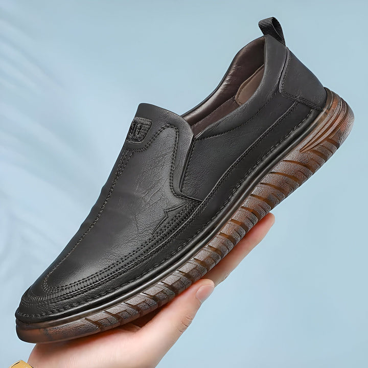 Mocassin en cuir noir pour homme, souligné par une main. Chaussure décontractée avec semelle marron texturée. Idéal pour un style élégant et confortable., 45286930940085,45286930972853,45286931005621,45286931038389,45286931071157,45286931103925,45286931136693,45286931169461,45286931202229,45286931234997,45286931267765,45286931300533,45286931333301,45286931366069,45286931398837,45286931431605,45286931464373,45286931497141,45286931529909,45286931562677,45286931595445