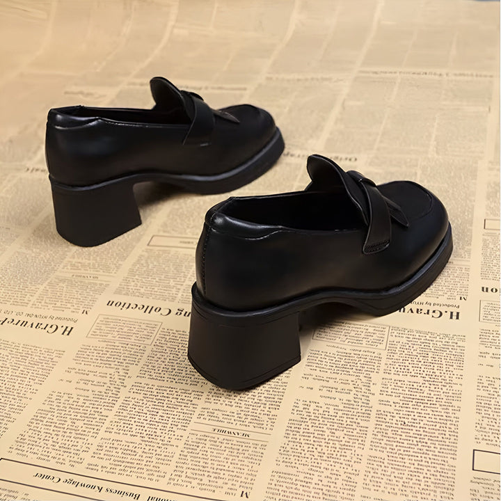 Une paire d'élégantes chaussures à talons noirs de style mocassins reposant sur un journal. Les chaussures ont une boucle décorative sur le dessus et un talon bloc épais., 45286630883509,45286630916277,45286630949045,45286630981813,45286631014581,45286631047349,45286631080117,45286631112885,45286631145653,45286631178421,45286631211189,45286631243957,45286631276725,45286631309493