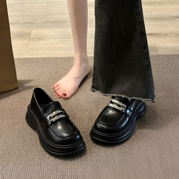 Gros plan sur une paire de mocassins noirs à semelles épaisses et ornements argentés. On voit une personne, pied nu à côté, et l'autre portant un jean noir évasé. Chaussures tendance et confortables., 45286686064821,45286686097589,45286686130357,45286686163125,45286686195893,45286686228661,45286686261429,45286686294197,45286686326965,45286686359733