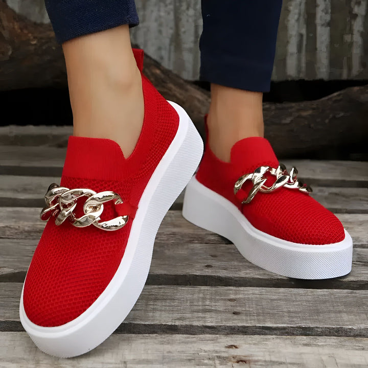 Gros plan de chaussures rouges avec une chaîne dorée, portées sur un plancher en bois. Les chaussures ont une semelle blanche épaisse., 45286881886389,45286881919157,45286881951925,45286881984693,45286882017461,45286882050229,45286882082997,45286882115765,45286882148533,45286882181301,45286882214069,45286882246837,45286882279605,45286882312373,45286882345141,45286882377909,45286882410677,45286882443445,45286882476213,45286882508981,45286882541749,45286882574517,45286882607285,45286882640053,4528688267