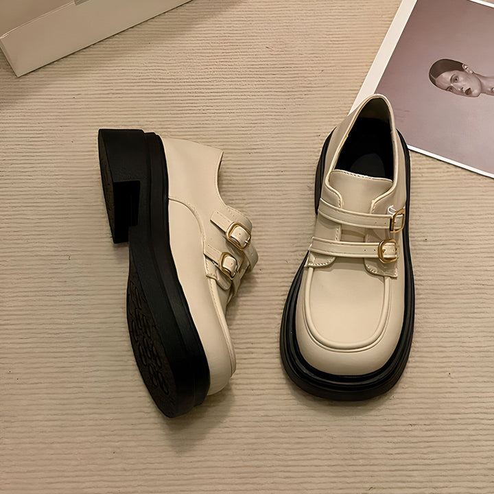 Vue rapprochée de chaussures compensées en cuir crème avec des boucles dorées. Elles ont des semelles noires épaisses et sont posées sur un fond beige texturé, à côté d'une boîte et d'une photo encadrée., 45286872547509,45286872580277,45286872613045,45286872645813,45286872678581,45286872711349,45286872744117,45286872776885,45286872809653,45286872842421,45286872875189,45286872907957