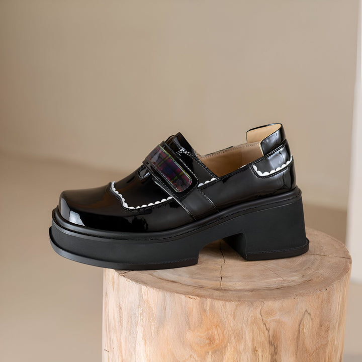 Chaussure Mary Jane noire vernie avec bride à carreaux et semelle plateforme épaisse, posée sur un tabouret en bois. Détails festonnés blancs. Mode et style féminin., 45286832013493,45286832046261,45286832079029,45286832111797,45286832144565,45286832177333,45286832210101