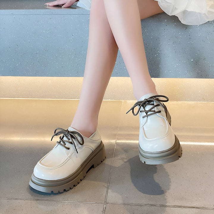 Gros plan des pieds d'une femme portant des chaussures derby blanches vernies à plateforme marron, lacets foncés. Style à la mode., 45286834995381,45286835028149,45286835060917,45286835093685,45286835126453,45286835159221,45286835191989,45286835224757,45286835257525,45286835290293,45286835323061,45286835355829