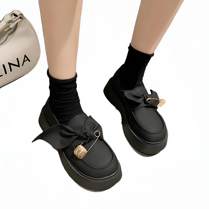 Chaussures compensées noires avec noeud, portées avec des chaussettes noires. Sac à main blanc visible en arrière-plan. Style de mode coréenne., 45286885359797,45286885392565,45286885425333,45286885458101,45286885490869,45286885523637,45286885556405,45286885589173,45286885621941,45286885654709,45286885687477,45286885720245