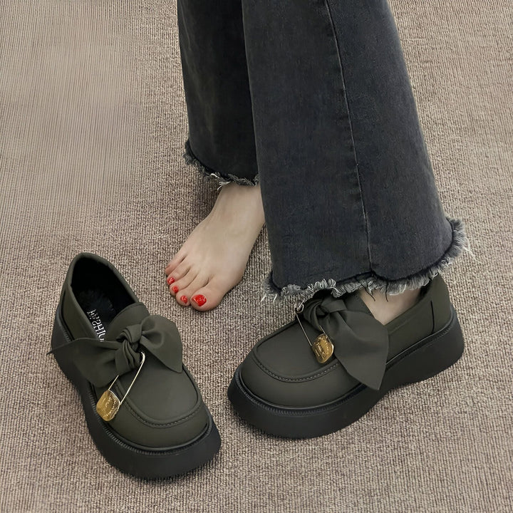 Mocassins vert olive à plateforme avec nœud et épingle à nourrice dorée, portés avec un jean gris foncé à ourlet effiloché. Un pied est nu., 45286885359797,45286885392565,45286885425333,45286885458101,45286885490869,45286885523637,45286885556405,45286885589173,45286885621941,45286885654709,45286885687477,45286885720245