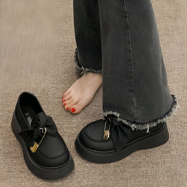 Chaussures mocassins noirs avec nœud et épingle à nourrice dorée, portées avec un jean évasé effiloché et vernis rouge, style mode grunge., 45286885359797,45286885392565,45286885425333,45286885458101,45286885490869,45286885523637,45286885556405,45286885589173,45286885621941,45286885654709,45286885687477,45286885720245