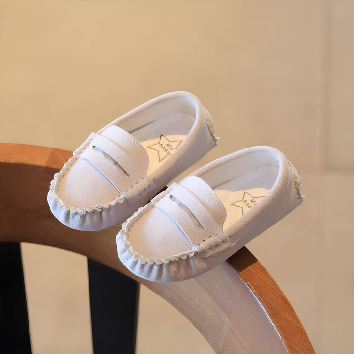 Mocassins blancs pour bébé, posés sur une chaise en bois. Les chaussures ont des détails en relief sur le dessus et une bordure festonnée. Marque "MG Baby" visible à l'intérieur., 45286765002933,45286765035701,45286765068469,45286765101237,45286765134005,45286765166773,45286765199541,45286765232309,45286765265077,45286765297845,45286765330613,45286765363381,45286765396149,45286765428917,45286765461685,45286765494453,45286765527221,45286765559989,45286765592757,45286765625525,45286765658293,45286765