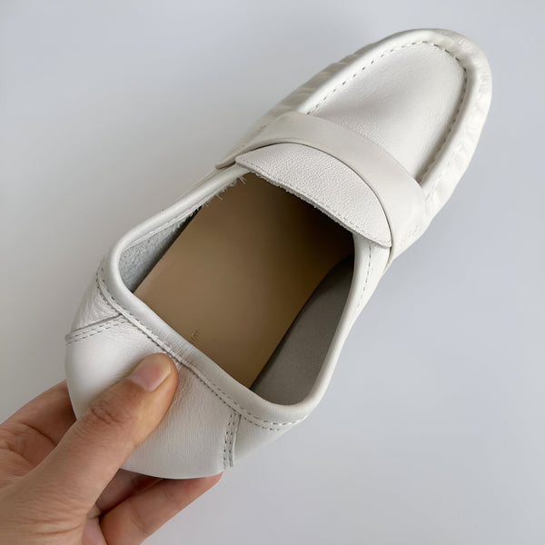 Vue rapprochée d'un mocassin blanc en cuir, tenu par une main. Chaussure élégante et confortable, idéale pour un look décontracté chic. Détails de couture visibles., 45286895485109,45286895517877,45286895550645,45286895583413,45286895616181,45286895648949,45286895681717,45286895714485,45286895747253,45286895780021,45286895812789,45286895845557,45286895878325,45286895911093,45286895943861,45286895976629,45286896009397,45286896042165