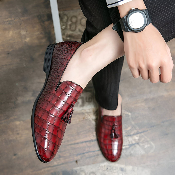 Vue plongeante d'un homme portant des mocassins en cuir rouge à motif crocodile avec glands, pantalon noir et montre-bracelet. Chaussures élégantes pour hommes., 45287062339765,45287062372533,45287062405301,45287062438069,45287062470837,45287062503605,45287062536373,45287062569141,45287062601909,45287062634677