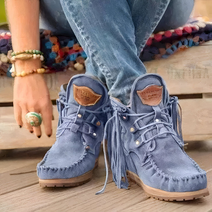 Gros plan sur des bottines bleues en daim à franges portées avec un jean, assise sur un banc en bois. On aperçoit une main avec des bracelets et une bague. Style bohème., 45286985236661,45286985269429,45286985302197,45286985334965,45286985367733,45286985400501,45286985433269,45286985466037,45286985498805,45286985531573,45286985564341,45286985597109,45286985629877,45286985662645,45286985695413,45286985728181,45286985760949,45286985793717,45286985826485,45286985859253,45286985892021,45286985924789,45286