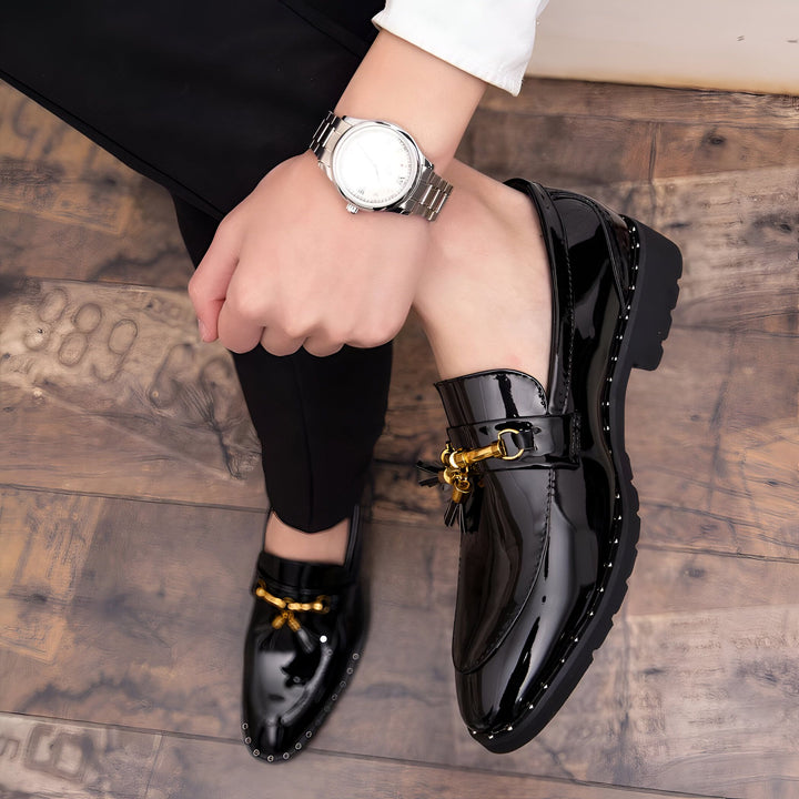 Gros plan de mocassins vernis noirs pour hommes, avec détails dorés, portés avec un pantalon noir et une chemise blanche. Une montre argentée est visible au poignet., 45286924910773,45286924943541,45286924976309,45286925009077,45286925041845,45286925074613,45286925107381,45286925140149,45286925172917,45286925205685,45286925238453,45286925271221,45286925303989,45286925336757