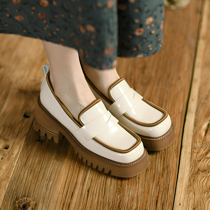 Gros plan sur des mocassins vernis crème avec bordure marron et semelle épaisse crantée, portés avec une jupe imprimée sur un parquet en bois. Chaussures tendance et confortables., 45286885982389,45286886015157,45286886047925,45286886080693,45286886113461,45286886146229,45286886178997,45286886211765,45286886244533,45286886277301,45286886310069,45286886342837