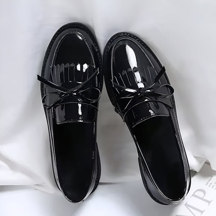 Vue rapprochée de deux mocassins vernis noirs avec des pompons et des petits nœuds, disposés sur un fond blanc. Chaussures élégantes et brillantes., 45286627442869,45286627475637,45286627508405,45286627541173,45286627573941,45286627606709,45286627639477,45286627672245,45286627705013,45286627737781,45286627770549,45286627803317,45286627836085,45286627868853,45286627901621,45286627934389