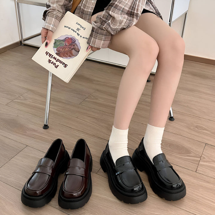 Une femme assise sur une chaise tient un livre intitulé "Pork Sandwich". On aperçoit des mocassins noirs brillants et bruns foncés au sol, ainsi que des chaussettes blanches., 45286831095989,45286831128757,45286831161525,45286831194293,45286831227061,45286831259829,45286831292597,45286831325365,45286831358133,45286831390901