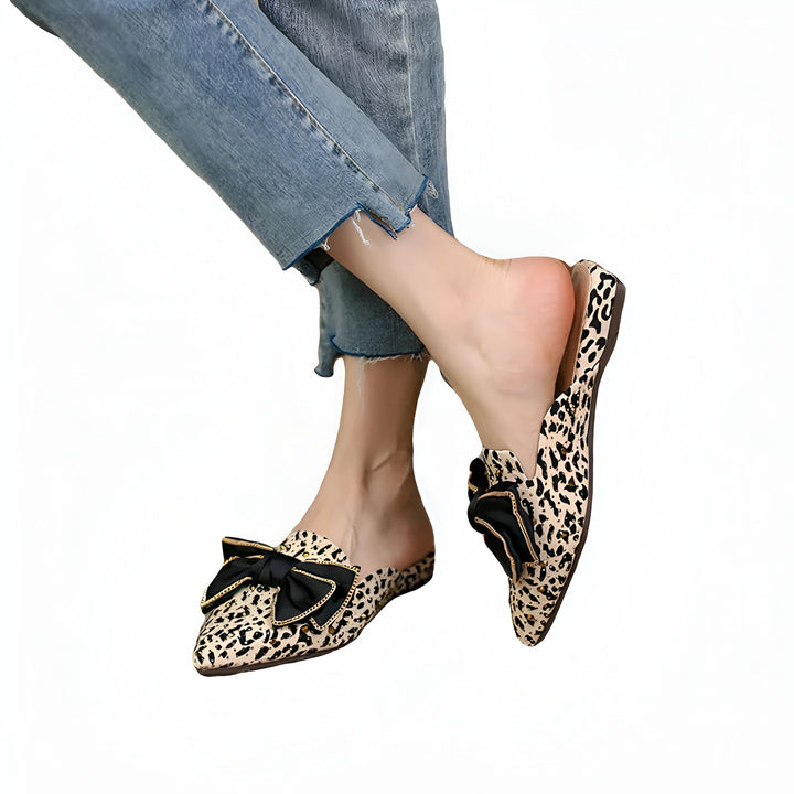 Chaussures plates à imprimé léopard avec noeud noir, portées avec un jean bleu. Mule élégante pour femme., 45287150813365,45287150846133,45287150878901,45287150911669,45287150944437,45287150977205,45287151009973,45287151042741